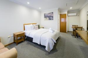 塔姆沃思Roydons Motor Inn的酒店客房设有一张大床和一张桌子。