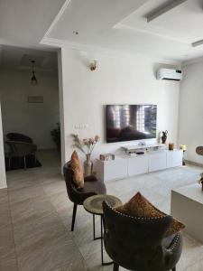 伊凯贾Dvyne Luxury Home的客厅配有椅子和墙上的电视