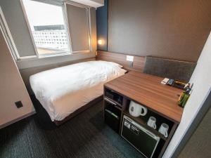 奈良Super Hotel Premier JR Nara Eki的小房间设有床、书桌和窗户