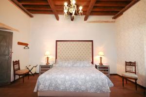 雷亚尔卡托尔塞Casa Grande - Adults Only的一间卧室配有一张带两把椅子的床和吊灯。
