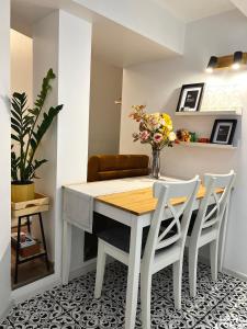 里加GREEN Apartment的餐桌,配有白色椅子和花瓶