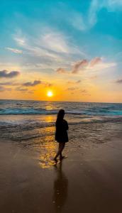 阿鲁特伽马Lucky Prince Villa的日落时在海滩上散步的女人