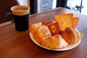 大阪HOTEL WAN OSAKA EBISU的一盘面包和羊角面包以及一杯咖啡