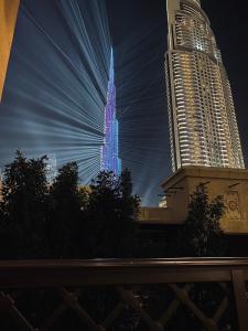 迪拜Lux Burj views -Boulevard -Prime Location Downtown DUBAI的一座高耸的摩天大楼在晚上被亮蓝色