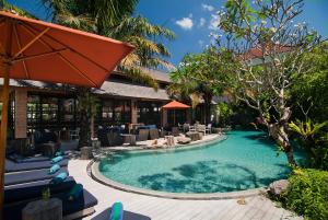塞米亚克Maca Villas & Spa Bali的一个带椅子和遮阳伞的度假村游泳池