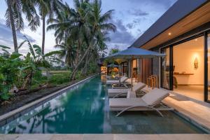 乌布Villa Surga - 4BR Heavenly Ricefields View Villa in Ubud的房屋旁设有带椅子和遮阳伞的无边泳池