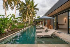 乌布Villa Surga - 4BR Heavenly Ricefields View Villa in Ubud的一座房子旁的游泳池,配有躺椅和遮阳伞