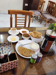 新德里Hotel Marina Near IGI Airport Delhi的餐桌上放有食物和面包的盘子