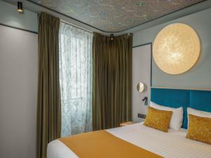 巴黎路易松酒店的一间卧室设有一张床和一个大窗户