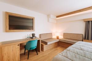 布勒伊-切尔维尼亚Valtur Cervinia Cristallo Ski Resort的配有床、书桌和四柱床的客房