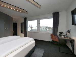 柏林B&B Hotel Berlin City-West的配有一张床、一张书桌和一扇窗户的酒店客房