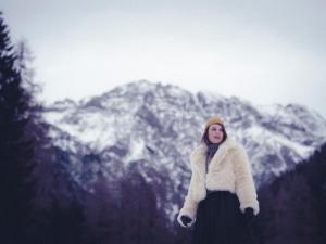 Sankt Lorenzen im LesachtalAlmwellness-Resort Tuffbad的站在雪覆盖的山前的妇女