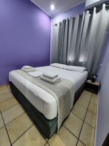 干尼亚Nina Apartment的紫色卧室配有两张带毛巾的床