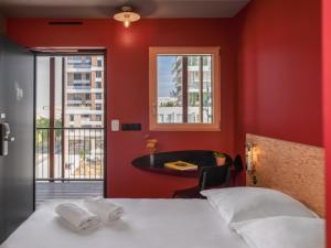 图卢兹Eklo Toulouse的卧室设有红色的墙壁、一张床和一张桌子