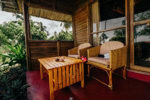 基林多尼Maisara Mafia Beach Lodge的门廊上配有桌椅的房间