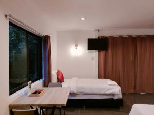 拉廊THANSILA Resort的一间卧室配有一张床、一张桌子和一个窗户。