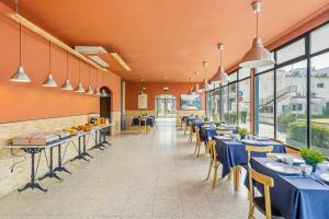 普拉加德阿罗Hostal La Marina的餐厅设有蓝色的桌椅和窗户。