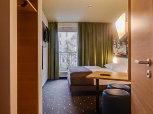 不来梅港B&B Hotel Bremerhaven的配有一张床、一张书桌和一扇窗户的酒店客房