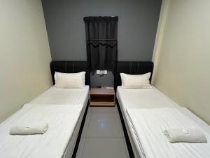 关丹格邦工业园经济型酒店的小客房内的两张床,配有白色床单
