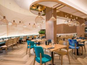 尼斯诺富特尼斯阿里纳斯阿罗伯特酒店的餐厅设有木桌和蓝色椅子