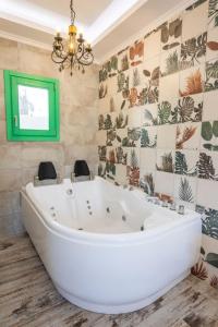 卡尔帕索斯La Scala Luxury Villa Μikis Theodorakis with jacuzzi的带绿色窗户的浴室内的白色大浴缸