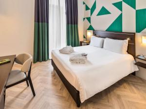 那不勒斯那不勒斯中心安吉尼奥美居酒店的酒店客房带一张大床,带毛巾
