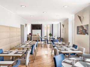 那不勒斯那不勒斯中心安吉尼奥美居酒店的一间配备有桌子和蓝色椅子的用餐室