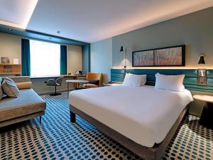 卢森堡卢森堡基希贝格诺富特酒店的酒店客房设有一张大床和一张沙发。