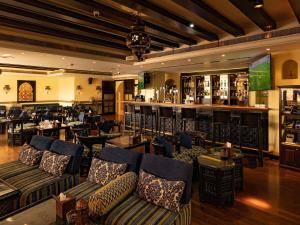 麦纳麦Mercure Grand Hotel Seef - All Suites的一间配有沙发的餐厅和一间酒吧