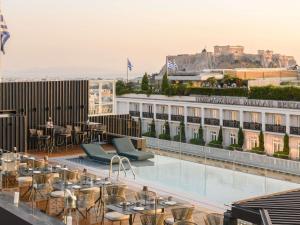 雅典Athens Capital Center Hotel - MGallery Collection的大楼内带桌椅的屋顶露台