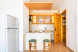 阿尔图拉Apartamentos Turisticos Alagoa Praia的厨房配有2把吧台凳和1台冰箱