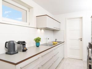 坎彭Kliffsand-72的白色的厨房配有白色橱柜和窗户