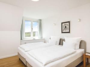 坎彭Kliffsand-72的白色客房的两张床,设有窗户