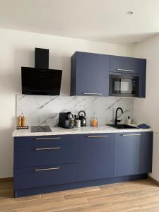 Cosy Appart’ & spa - Appartement privatif - baignoire balnéothérapie的厨房配有蓝色橱柜和台面