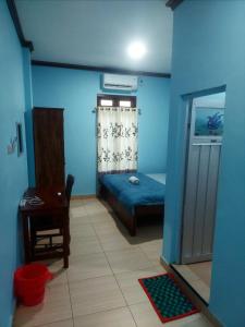 纳闽巴霍D'Ru Guest House的一间拥有蓝色墙壁的卧室,配有一张床和一张桌子