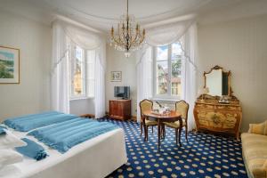 贝拉吉奥Grand Hotel Villa Serbelloni - A Legendary Hotel的一间卧室配有两张床、一张桌子和一个吊灯。