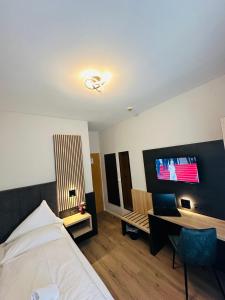 埃默里希艾梅里希斯达德特酒店的一间卧室配有一张床、一张书桌和一台电视。