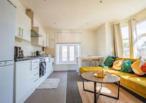 伦敦Guest Homes - Lewisham Flat的厨房以及带黄色沙发的起居室。