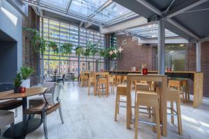 布雷达Leonardo Hotel Breda City Center的餐厅设有木桌、椅子和窗户。