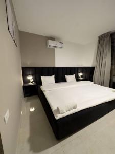安曼Stylish Luxe Apartment的一间卧室配有一张带两盏灯的大型白色床。