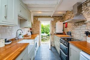 斯沃尼奇Cosy Little Hyde Cottage, Swanage的厨房配有白色橱柜和石墙