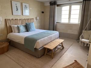 阿尔卜Ogygia Suites Gozo的一间卧室配有一张床、一张长凳和一个窗户。