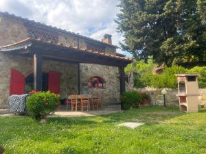 Badia A PassignanoIl Fiorino di Badia的石头房子,设有红色的门和桌椅