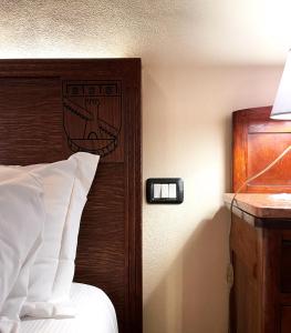 Sala Bolognese米内利广场酒店的一间卧室配有一张带木制床头板的床