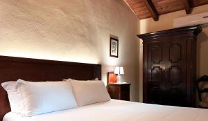 Sala Bolognese米内利广场酒店的卧室配有白色的床和木制床头板