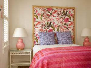 哈勃岛Eleven Bahama House的一间卧室配有一张带花卉床头板的床和两盏灯。