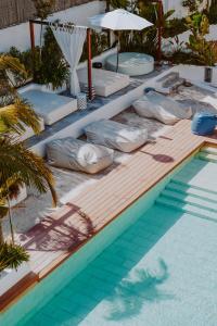 圣埃乌拉利亚Nativo Hotel Ibiza的游泳池旁的游泳池配有枕头和遮阳伞