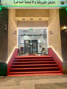 麦加Najmat Alnoor Almaabdah Hotel的一座铺有红地毯的建筑中的楼梯