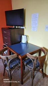 乌斯怀亚Mirador del Beagle Hosteria的一张带两把椅子的木桌和一台电视