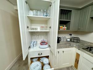 布莱尔高里Struan House的厨房配有带盘子和盘子的白色橱柜